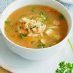 DALL·E 2024 05 29 11.39.15 A photo showing fresh ingredients for a homemade chicken soup. Includes 500g of raw chicken breast a large onion two garlic cloves two carrots two 1