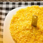 DALL·E 2024 05 30 16.29.23 A table with all the ingredients for making traditional Cuscuz de Milho Nordestino 2 cups of flaked cornmeal 1 cup of water 1 2 teaspoon of salt 1