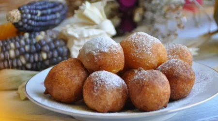 DALL·E 2024 06 07 09.36.10 A high quality image of Bolinho de Chuva de Leite Ninho ready to serve. The bolinhos are arranged on a plate dusted with a generous amount of sugar a 1